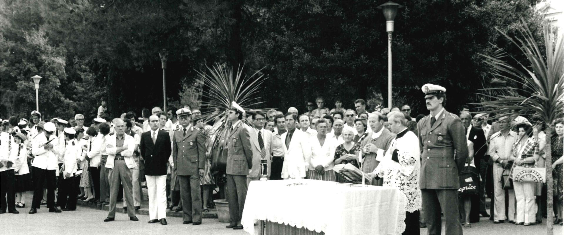 Celebrazione della liturgia da parte del Vescovo con un altare posizionato nel parco Indipendenza ora Federico Fellini con ai lati i Vigili Urbani schierati in alta uniforme e attorniato dal pubblico. Uno dei due Vigili è il pugile Alfio Righetti 