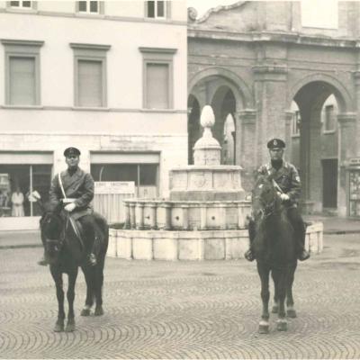 I Vigili Luigi Corbelli e Aldo Trovanelli in servizio a cavallo durante le domeniche senza auto. Si trovano in piazza Cavour davanti alla fontana della Pigna e alla vecchia pescheria. 